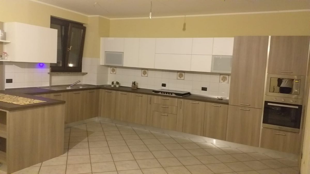 Ampia cucina ad angolo in rovere con pensili bianchi