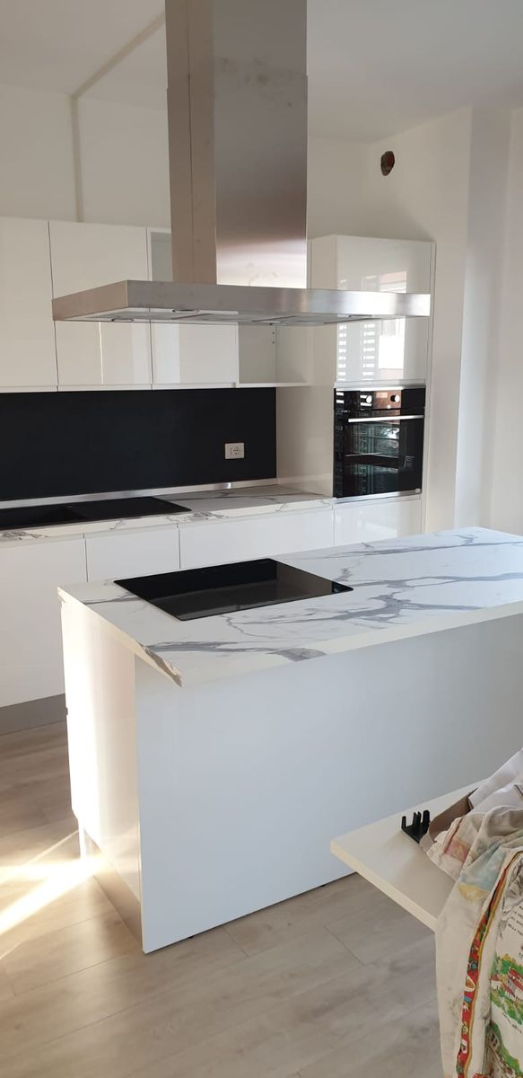 Cucina bianca con isola effetto marmo e cappa a soffitto