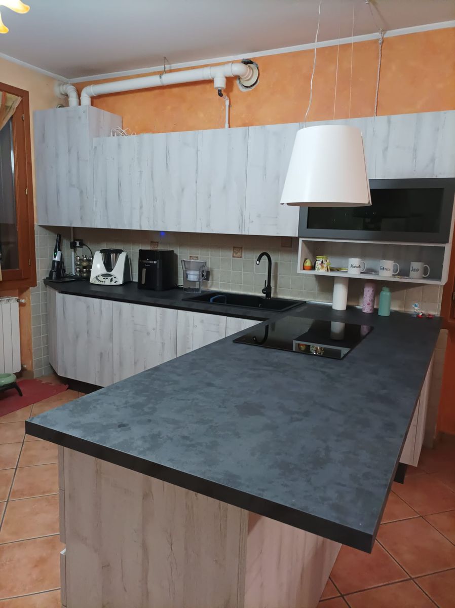 Cucina in legno chiaro con penisola e piano scuro