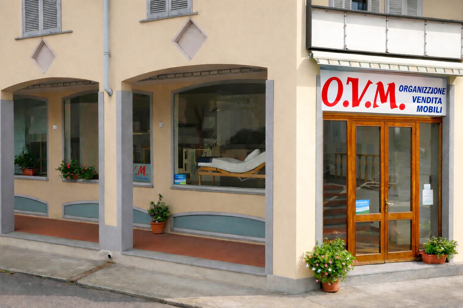 La facciata del negozio O.V.M. con le vetrine ad arco e l'insegna rossa